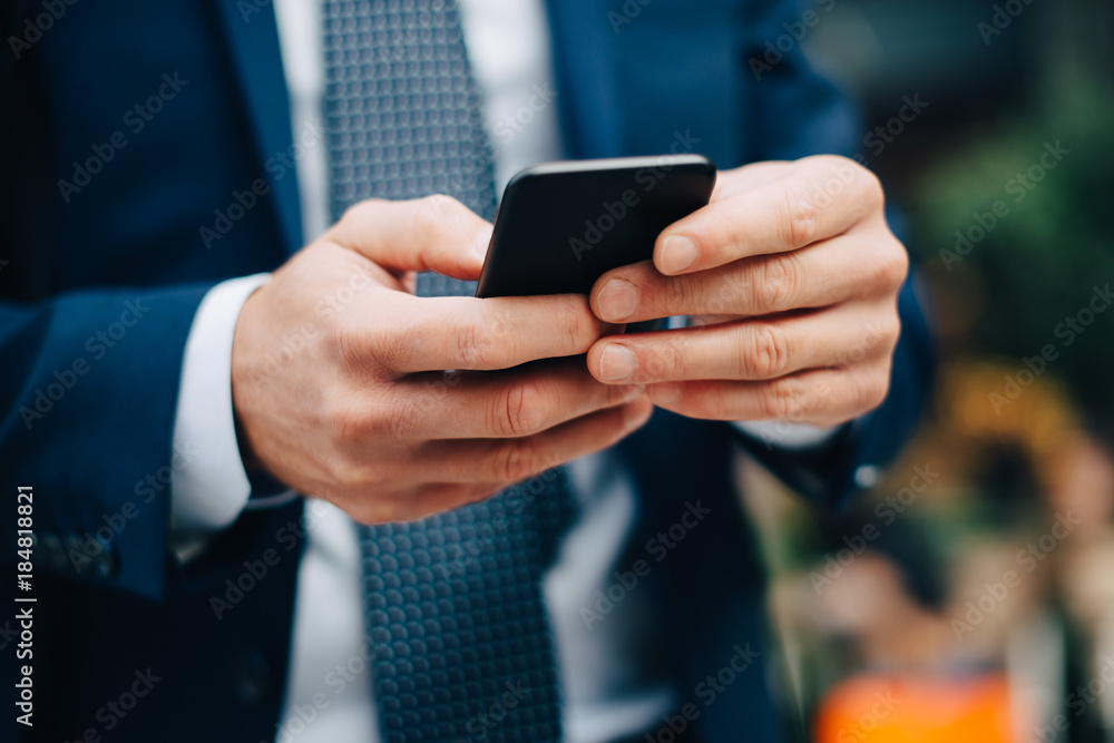 Midsection of mature businessman text messaging from smart phone in city Midsection of mature businessman text messaging from smart phone in city