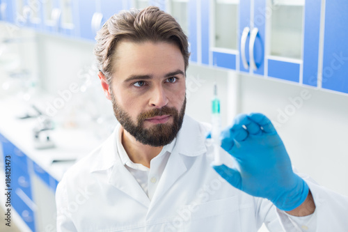 Smart male scientist looking at the syringe