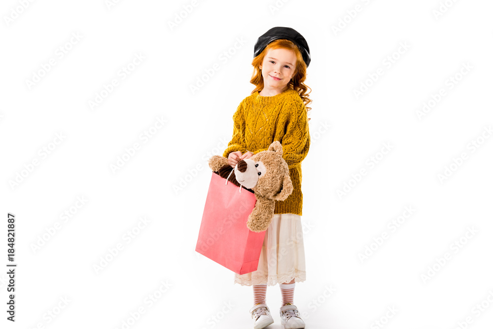 red hair child holding teddy bear in shopping bag isolated on white