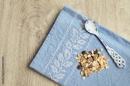 Muesli and spoon with a blue pattern on the background of a blue tablecloth with embroidery on a wooden background