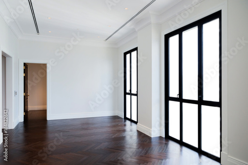 empty room interior with white wall and dark brown wood floor with light from window