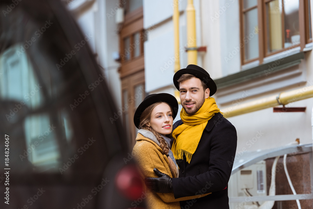 young attractive couple hugging behind car young attractive couple hugging behind car
