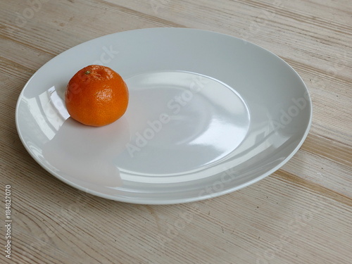 Bright orange satsuma on a white plate on a table