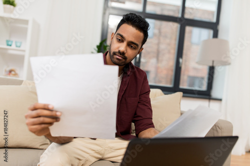 upset man with laptop and papers at home