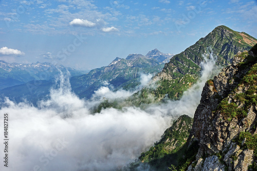 Panorama of the mountains in the area of Krasnaya Polyana/Panorama of Sochi in the Krasnaya Polyana area. There are mountains, clouds, air haze, vegetation. Sochi, Russia, mountain landscape 