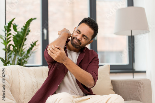 Photography unhappy man suffering from pain in hand at home