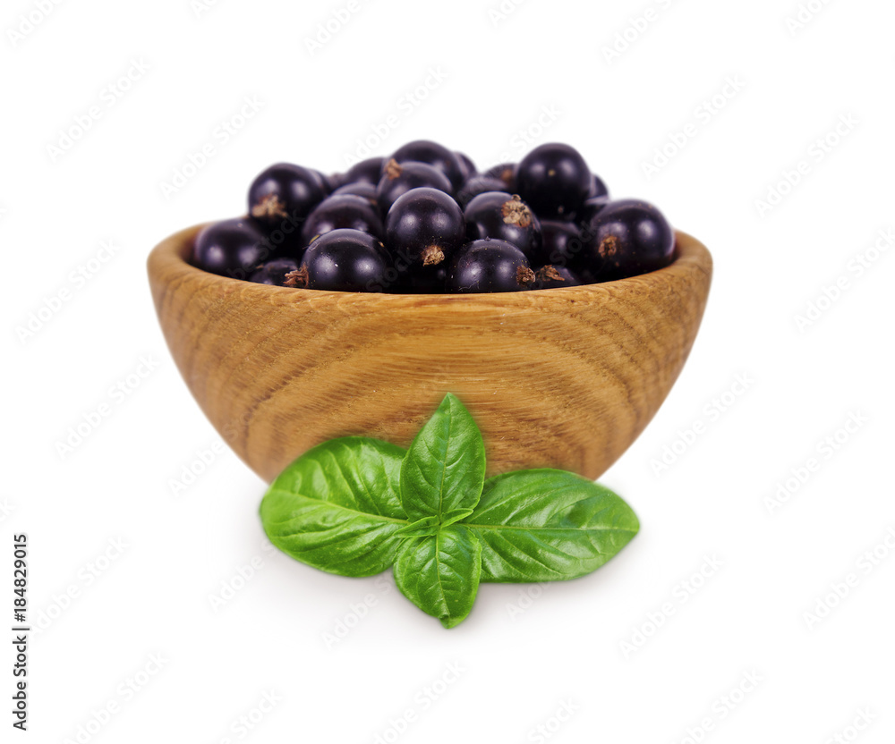 Blackcurrant with basil in a wooden bowl with copy space for text. Ripe and tasty black berry isolated on white. Currant on a white background. Blackcurrant with basil in a wooden bowl with copy space for text. Ripe and tasty black berry isolated on white. Currant on a white background.