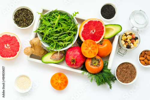 Healthy food in wooden tray  fruits  vegetables  seeds and greens on white background. Flat lay. Top view