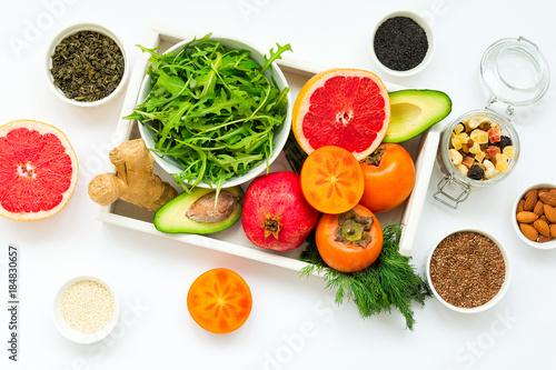 Healthy food in wooden tray: fruits, vegetables, seeds and greens on white background. Flat lay. Top view