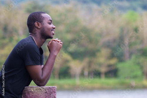 African man praying at the park.