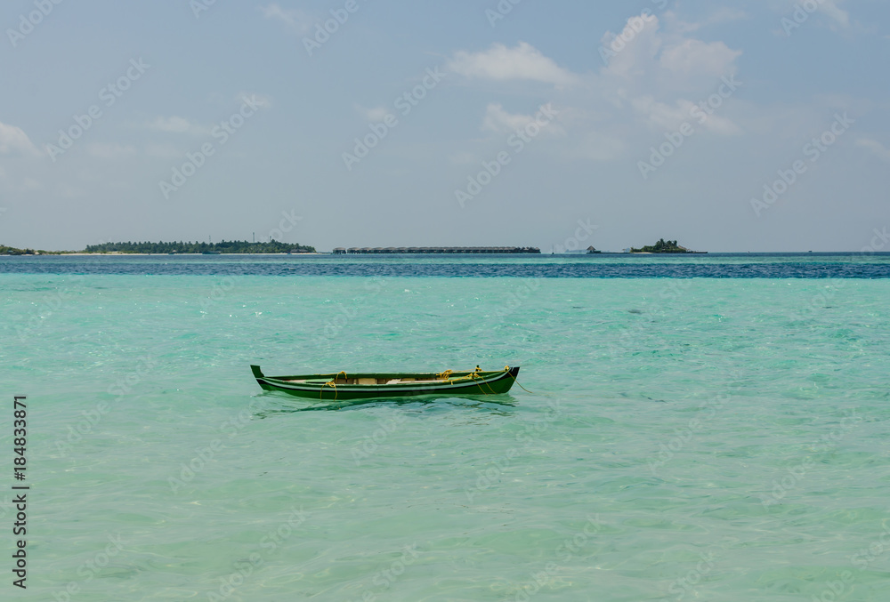 Maldives - November, 2017: Colorful wooden boat in the Indian Ocean, Maldives, horizon - tropical island and water villas against blue sky Maldives - November, 2017: Colorful wooden boat in the Indian Ocean, Maldives, horizon - tropical island and water villas against blue sky
