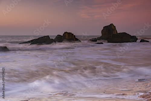 Pink sunrise over the sea and the rocks in the water with silk water