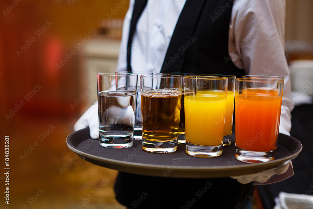 Glasses of drinks on a waiter's tray. New year or Christmas celebration Glasses of drinks on a waiter's tray. New year or Christmas celebration