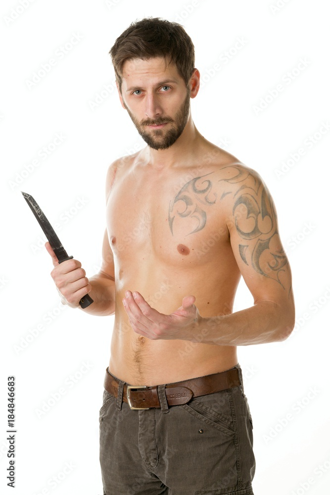 A man with a bandit's beard with a bare torso is holding a big knife in his hands against a white background A man with a bandit's beard with a bare torso is holding a big knife in his hands against a white background