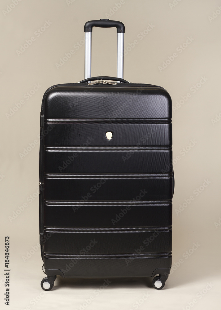Black trolley suitcase bag isolated on beige background Black trolley suitcase bag isolated on beige background