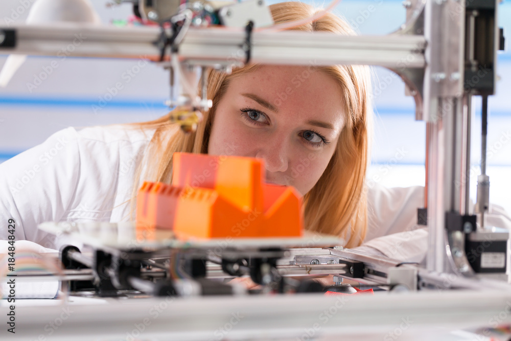 Fotografie A female student or laboratory assistant in the automation laboratory is debugging the work of the 3d printer