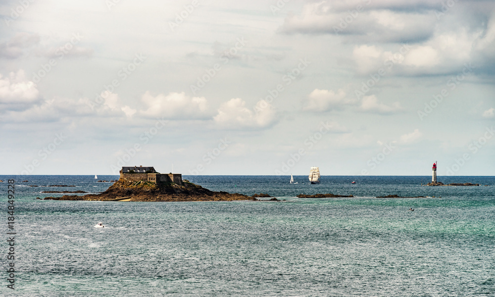 Seaside landscape with old medieval fort on the island, pirate frigate and lighthouse
