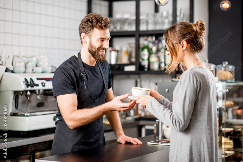 Φωτογραφία Handsome barista giving a coffee to the female client at the bar of the modern c