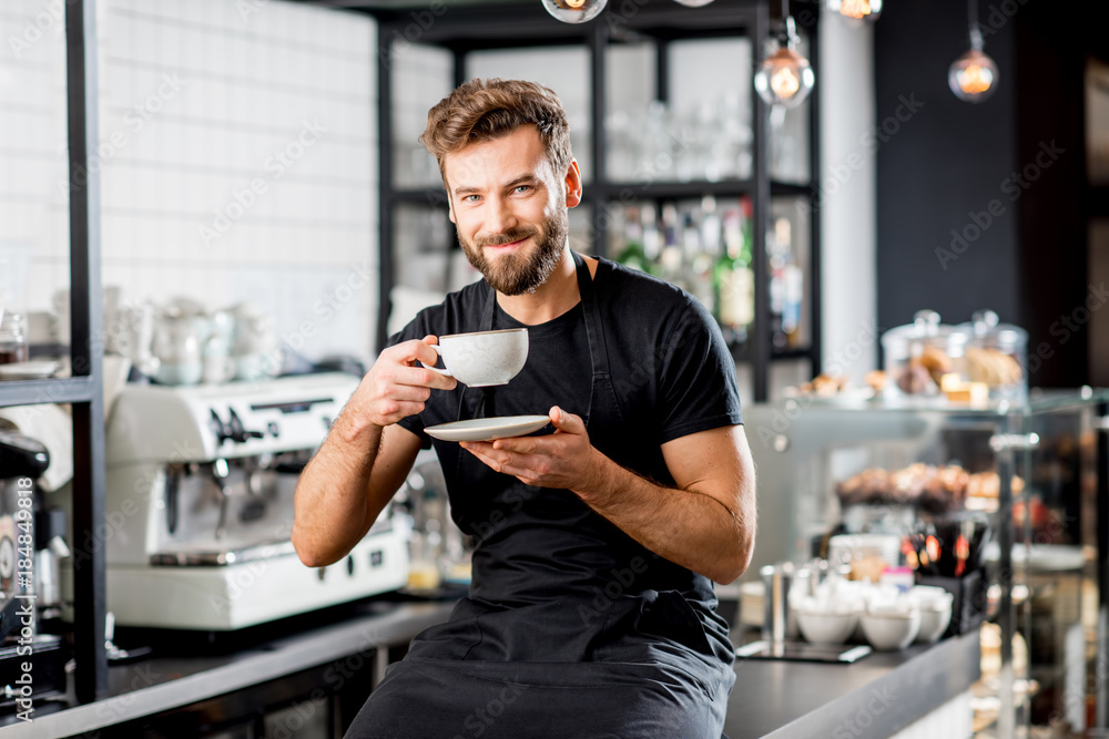 Φωτογραφία Portrait of a handsome barista sitting with coffee at the bar of the modern cafe
