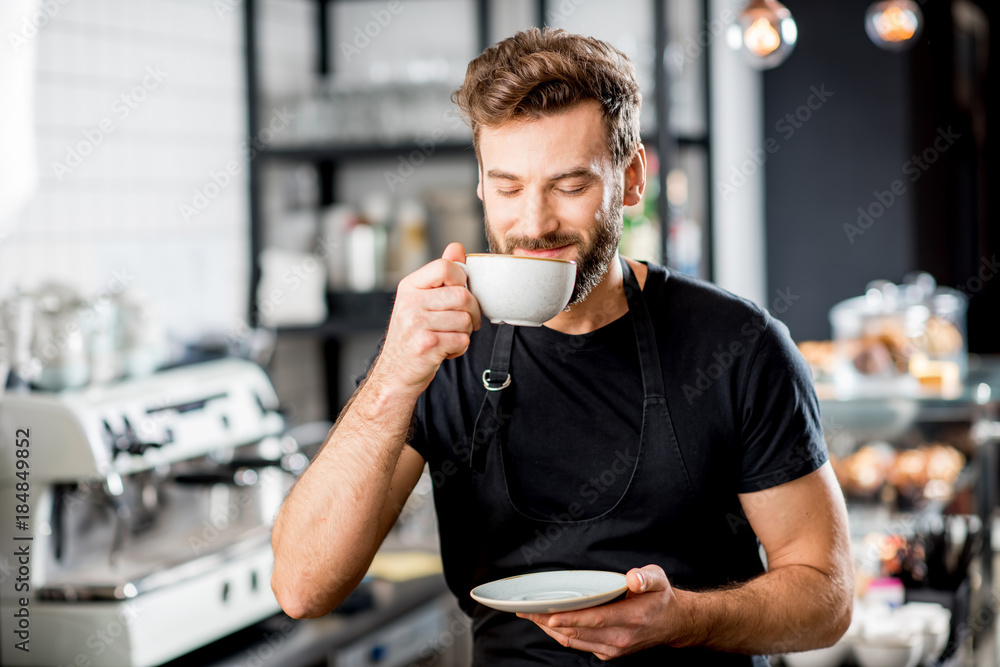 Φωτογραφία Portrait of a handsome barista sitting with coffee at the bar of the modern cafe