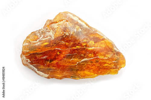 Technology of processing amber. A beautiful large piece of amber during polishing on a white background. Amber with polishing paste and traces of chalk. A natural mineral for jewelry. A sunstone. 