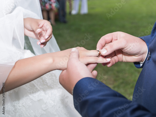 Groom puts in ring on bride s finger during wedding ceremony