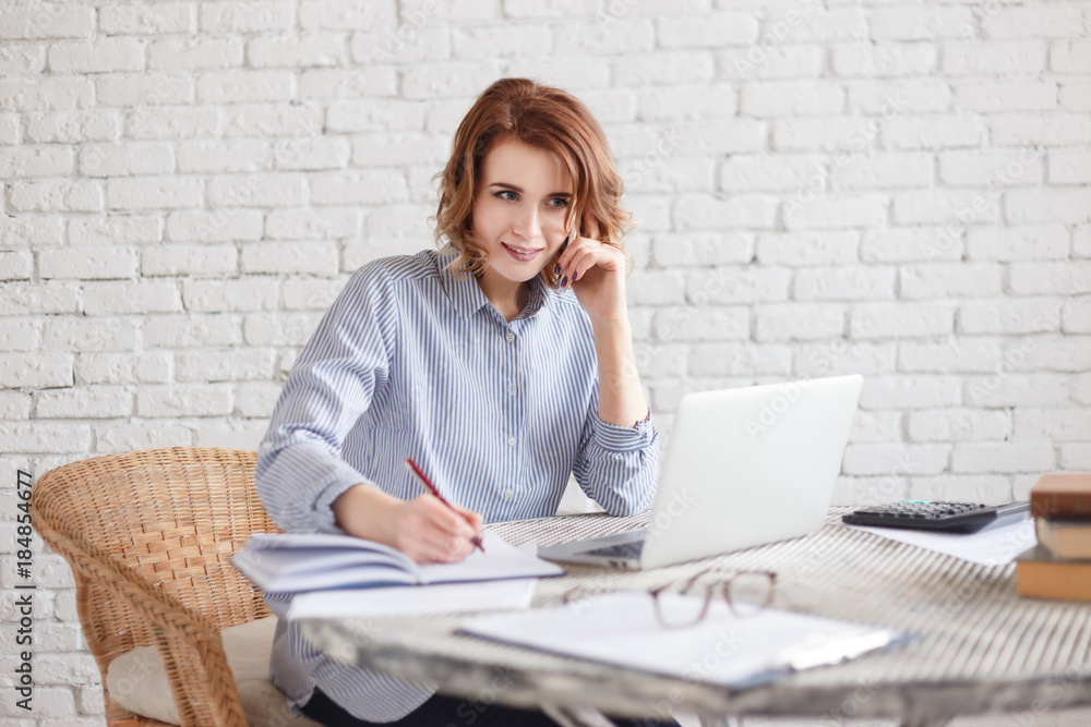 Happy smiling woman freelancer writes notes in a diary sitting in a office or at home Happy smiling woman freelancer writes notes in a diary sitting in a office or at home
