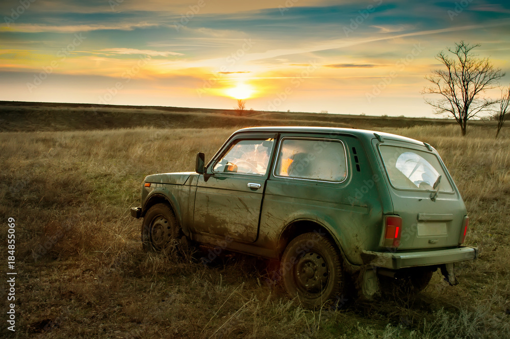 dirty SUV in the evening in the field - obrazy, fototapety, plakaty 