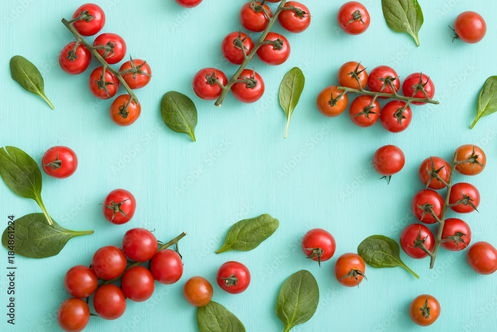 Top view on bunches of fresh organic cherry tomatoes with small basil leaves on turquoise background. Healthy food and eating concept. Top view on bunches of fresh organic cherry tomatoes with small basil leaves on turquoise background. Healthy food and eating concept.