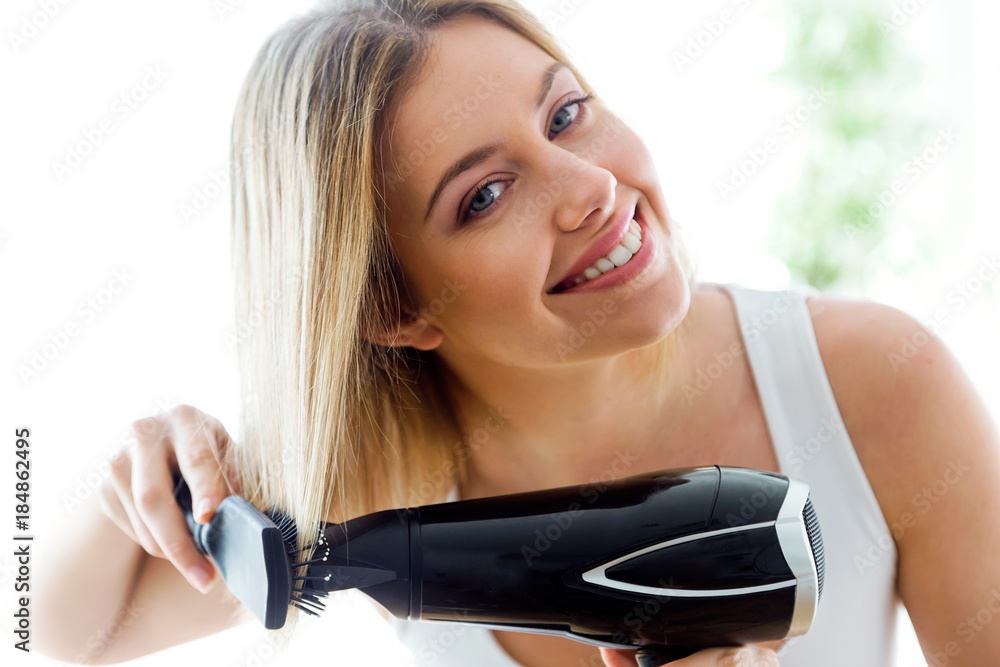 Beautiful young woman making hairstyle near mirror in the bathroom at home. Beautiful young woman making hairstyle near mirror in the bathroom at home.