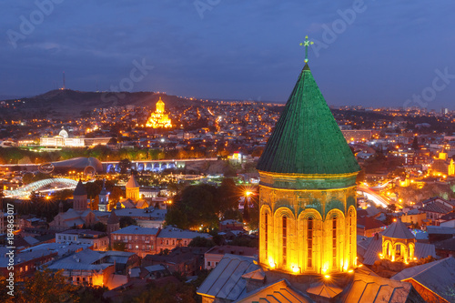 Aerial view of Old Town with dome of Lower Bethlemi Church and Sameba Holy Trinity Cathedral, Metekhi Church, bridge of Peace and Presidential Palace in night Illumination during evening blue hour photo