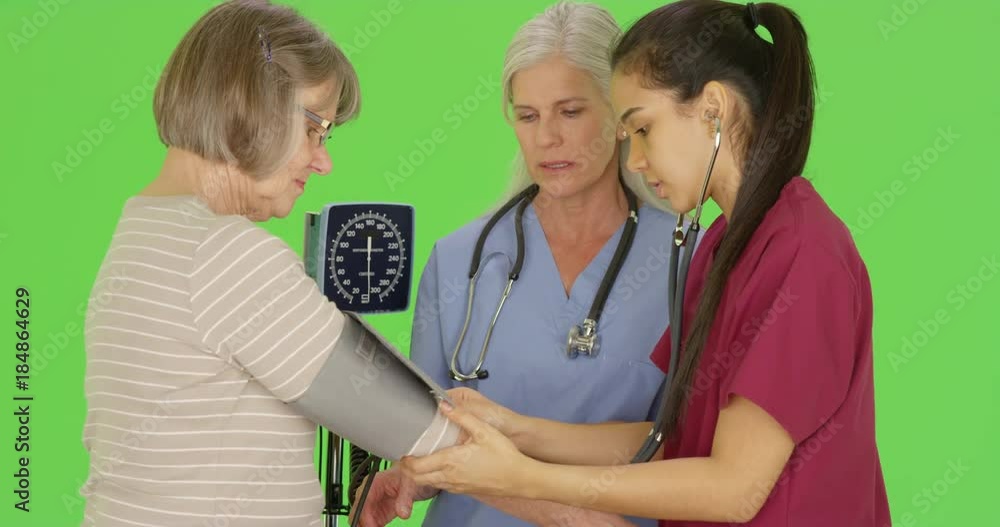 RN training nursing student to take senior patient blood pressure on green screen. On green screen to be keyed or composited. RN training nursing student to take senior patient blood pressure on green screen. On green screen to be keyed or composited.