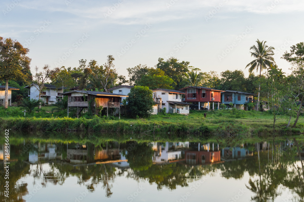 Wooden houses in countryside near the lake with mirror reflection in water