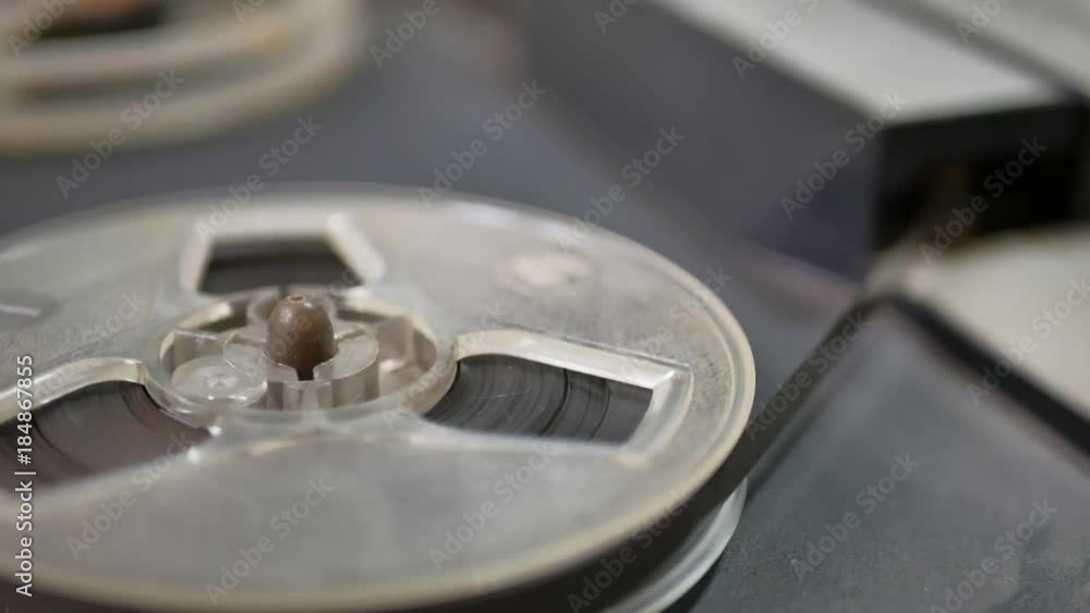 Old coil tape recorder with magnetic tape on reels. Reel with recording tape close up in reel-to-reel recorder. Old coil tape recorder with magnetic tape on reels. Reel with recording tape close up in reel-to-reel recorder.