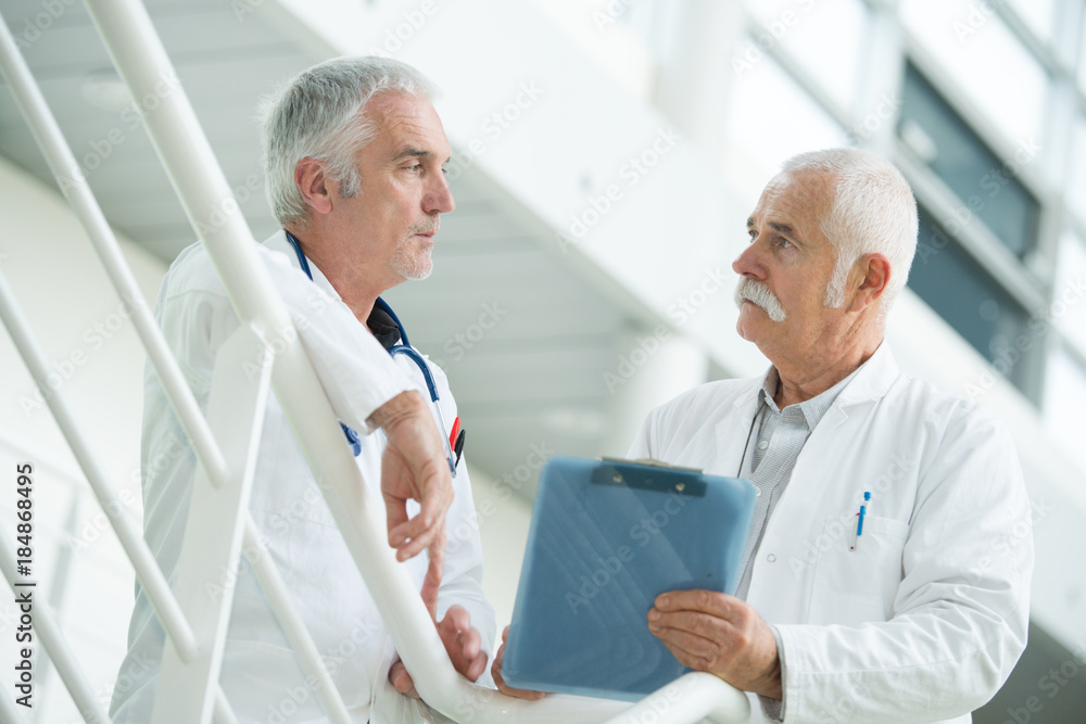 two doctors walking along hospital corridor two doctors walking along hospital corridor