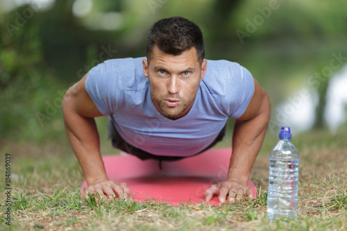 man doing push ups on grass in summer park photo