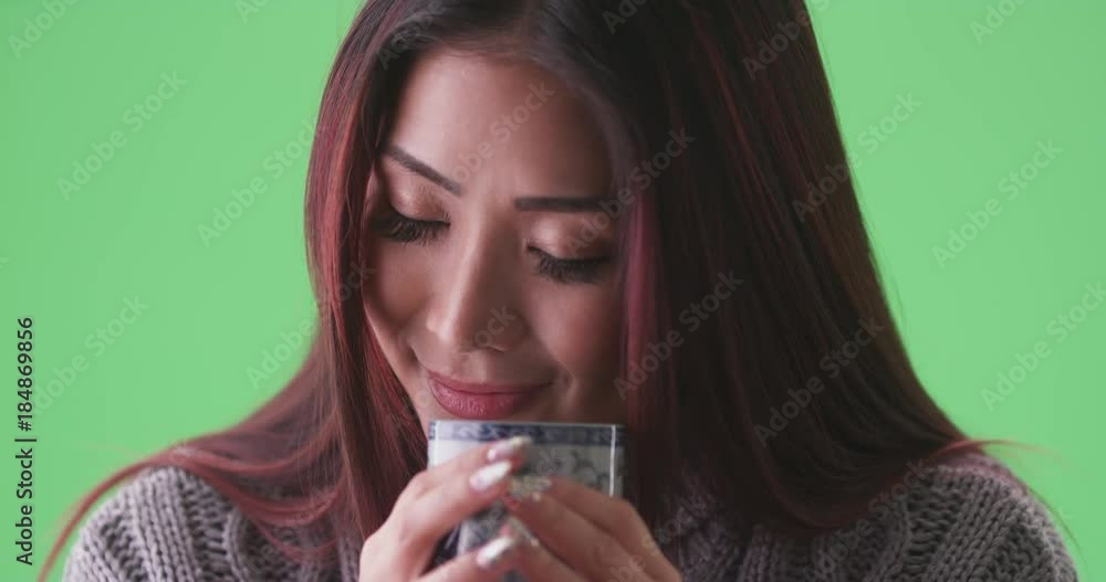 asian woman smelling her cup of tea on green screen. On green screen to be keyed or composited. asian woman smelling her cup of tea on green screen. On green screen to be keyed or composited.