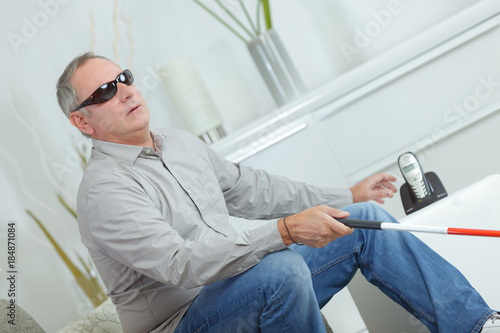mature blind man with stick and dark glasses at home