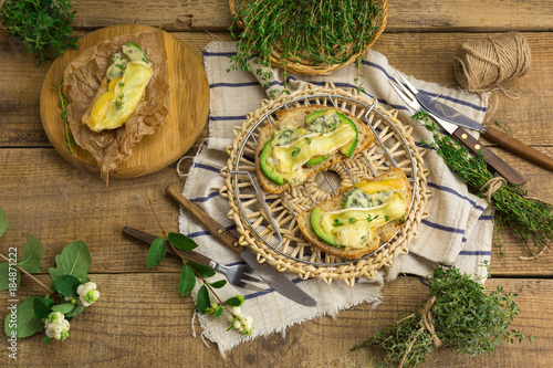 Healthy sandwiches with avocado, cheese and herbs. On wooden background.