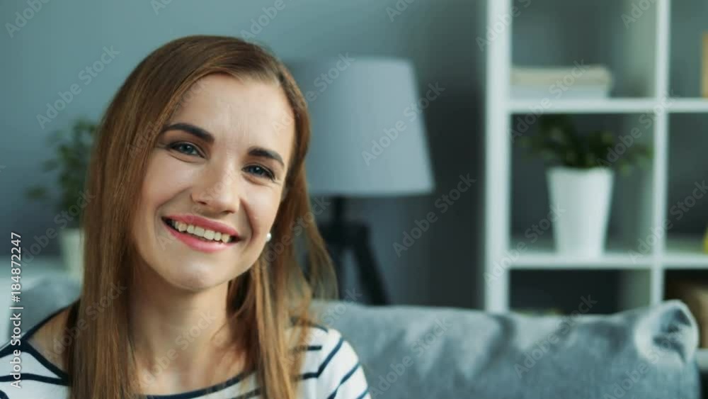 Attractive woman with long hair sitting on the couch in the living room and smiling into the camera. At home. Portrait. Close up. Indoors Attractive woman with long hair sitting on the couch in the living room and smiling into the camera. At home. Portrait. Close up. Indoors