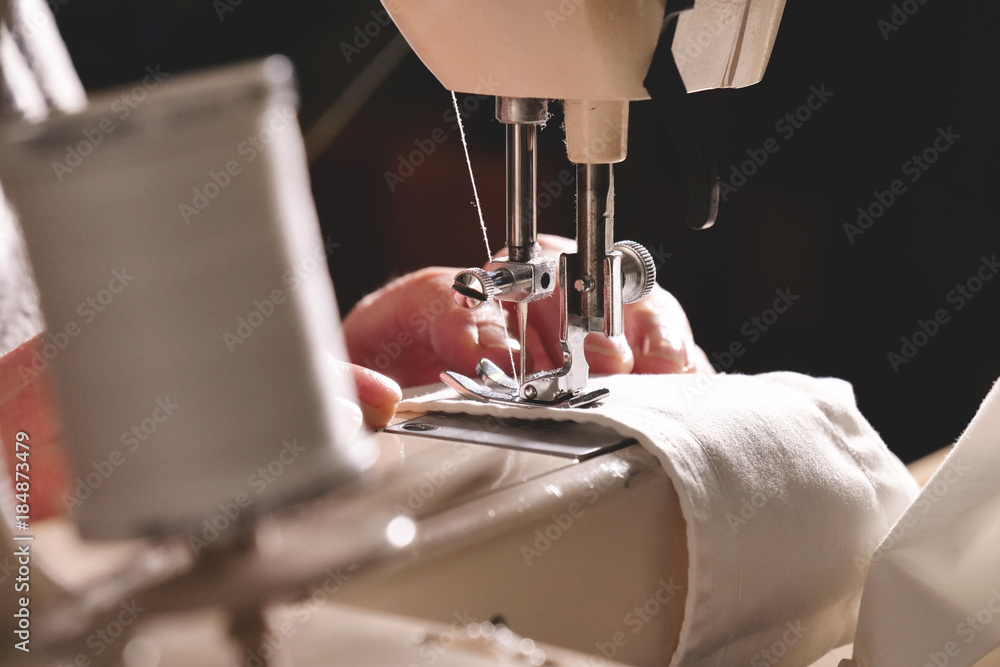Super slow motion of a professional sewing machine stitching with white thread an Italian haute couture fabric, The seamstress sews a high fashion outfit. concept of industry, tradition, fashion