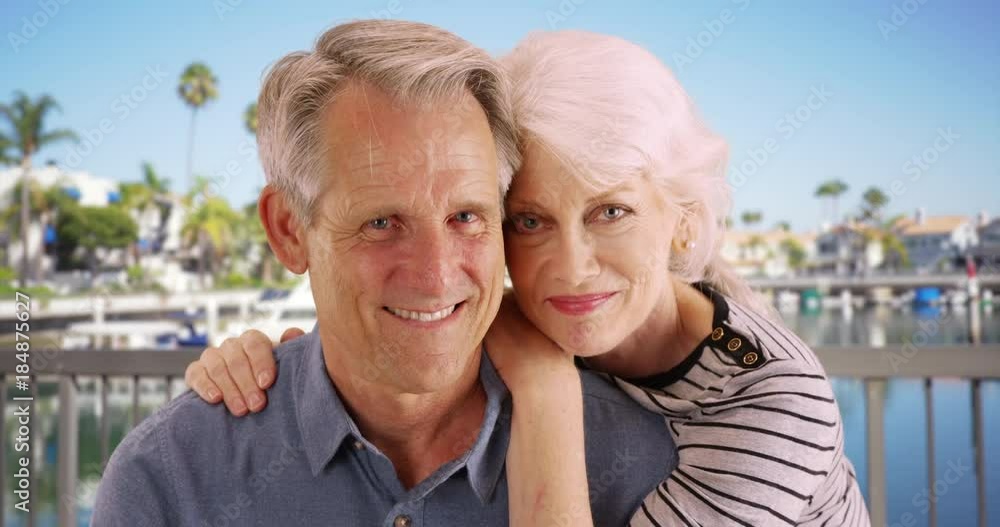 Senior couple sitting outdoors smiling at camera Senior couple sitting outdoors smiling at camera