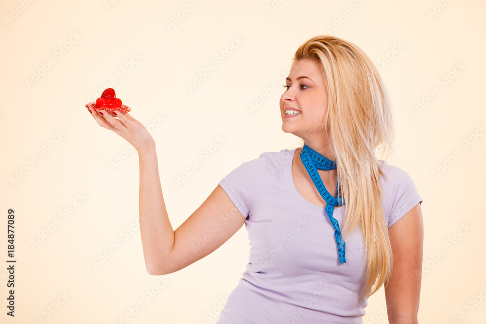 Woman with measuring tape holding sweet cupcake