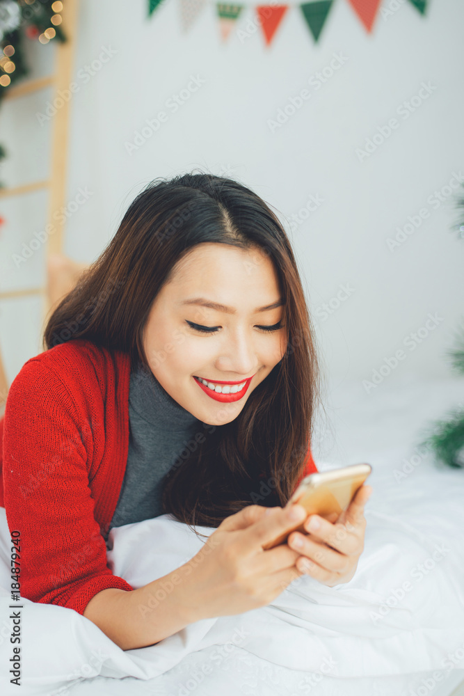Young smiling asian woman is using mobile phone. Christmas and New Year time Young smiling asian woman is using mobile phone. Christmas and New Year time