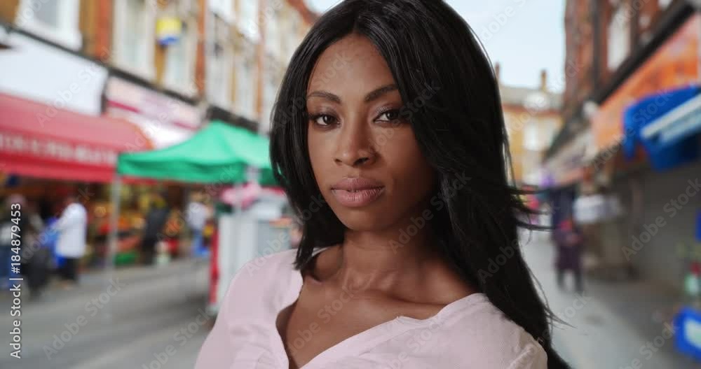 African-American female looks slyly at camera near street market in Brixton African-American female looks slyly at camera near street market in Brixton