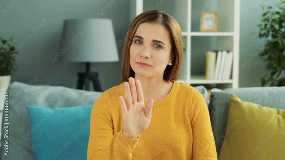 Good looking woman making stop movement with her hand and saying no by waving finger in the cozy home room. Close up. Portrait. Indoors Good looking woman making stop movement with her hand and saying no by waving finger in the cozy home room. Close up. Portrait. Indoors