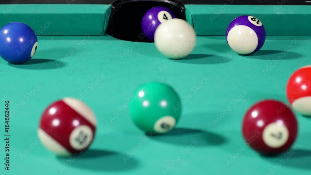 Close up of a white billiard ball hitting the billiard ball number four and get into the hole