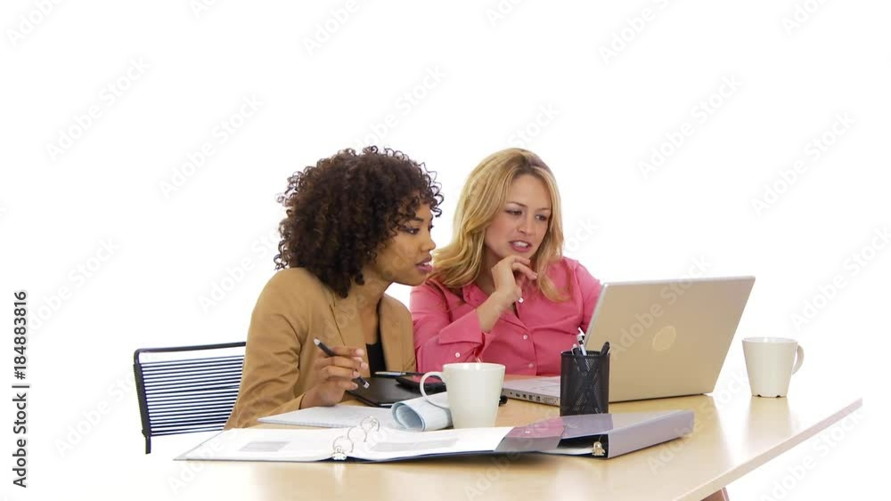 Two businesswomen working on laptop together looking concerned Two businesswomen working on laptop together looking concerned
