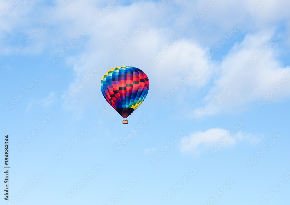 Colorful hot air balloon flying in the blue sky with soft clouds - at Winthrop Balloon Festival, Washington state Colorful hot air balloon flying in the blue sky with soft clouds - at Winthrop Balloon Festival, Washington state