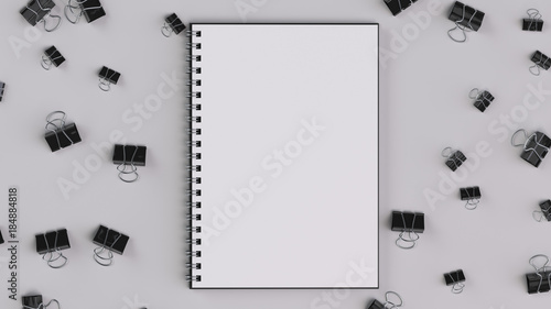 Blank spiral notebook with black binder clips on white table